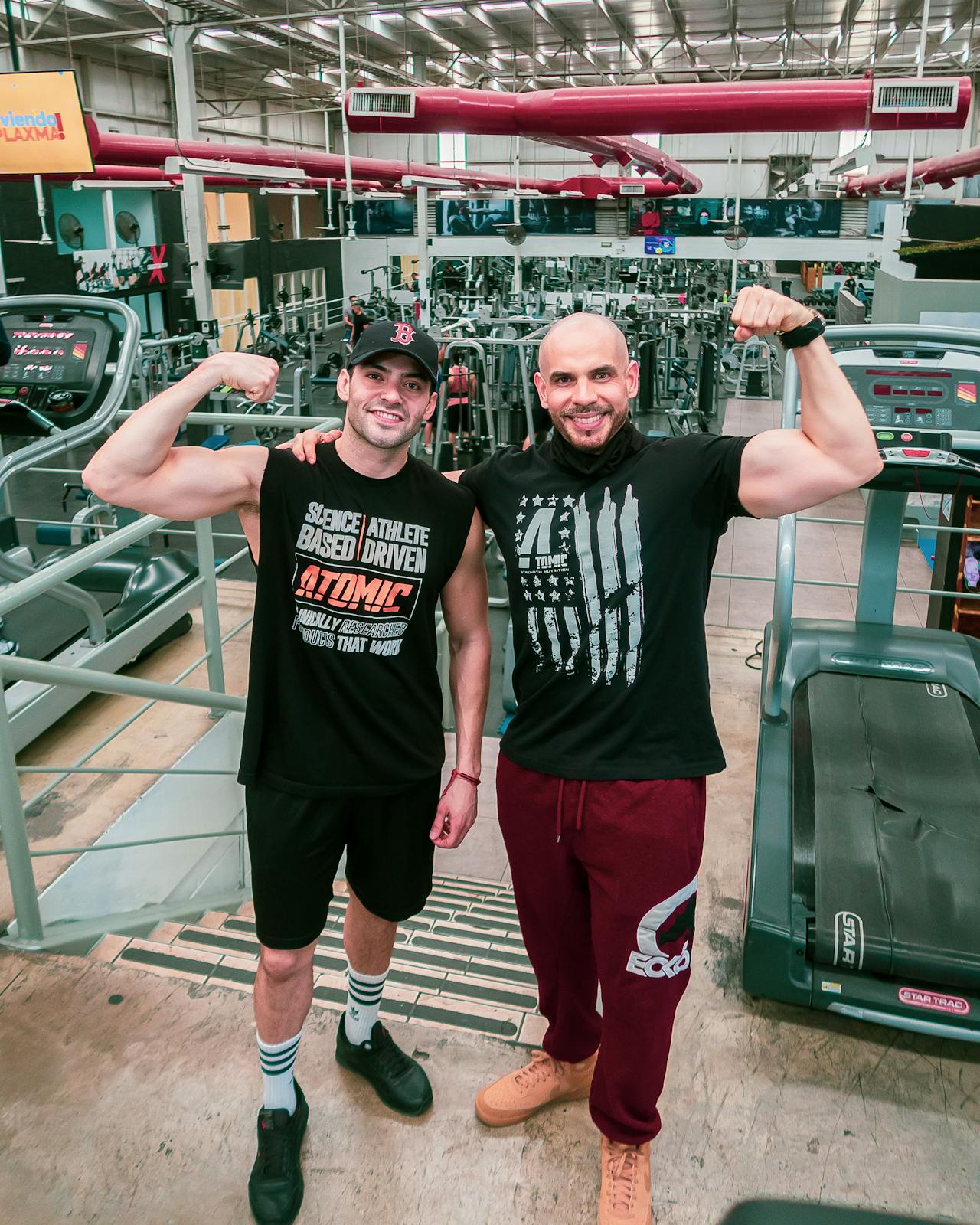 Twee gespierde mannen flexen samen hun biceps in de gym