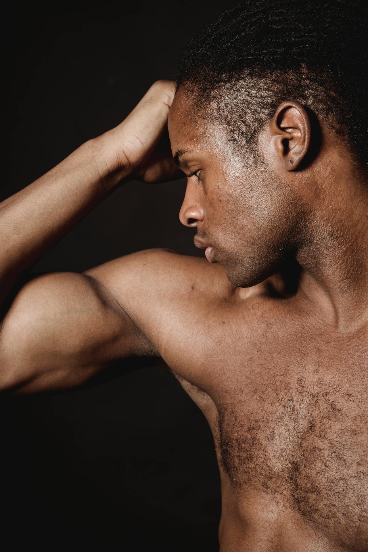 Peinzende man flext zijn biceps in dramatisch licht